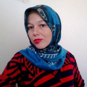 image of a white woman in a blue headscarf, with bold orange lipstick matching the stripes on her shirt